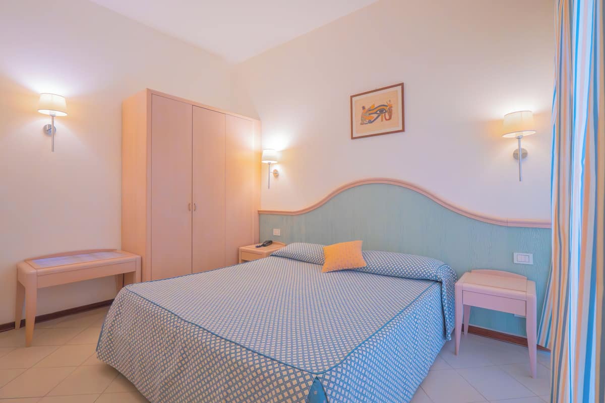Een slaapkamer met een bed, nachtkastjes, een kledingkast en wandlampen.