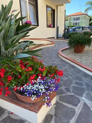 A pathway leading to a house with a stone-tiled entrance, surrounded by a variety of potted plants and flowers. - Hotel Splendid (Diano Marina)