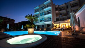 A swimming pool with a hot tub, lounge chairs, and umbrellas. - Hotel Splendid (Diano Marina)
