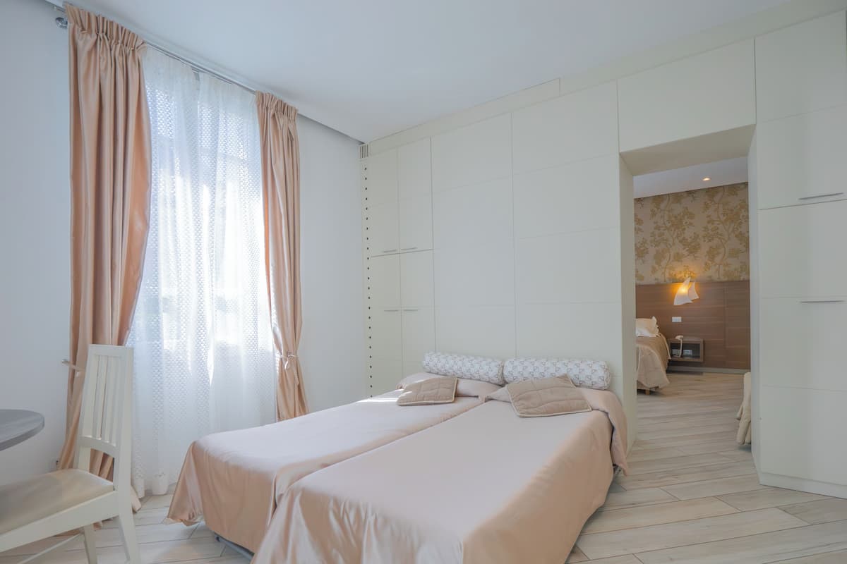 Een slaapkamer met twee bedden, een stoel en een klein tafeltje.