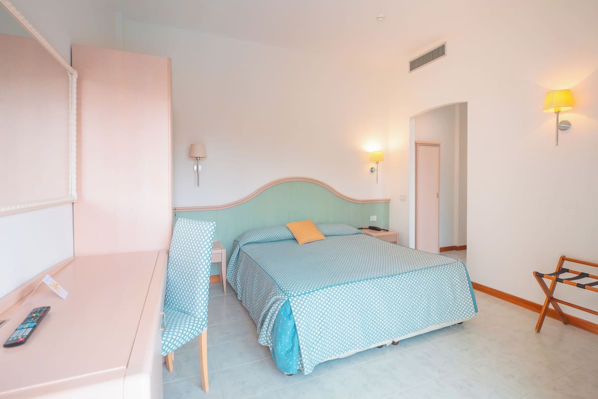 Een slaapkamer met twee bedden, een bureau, een stoel en een lamp.