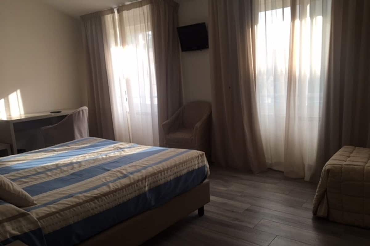 Een hotelkamer met een bed, een bureau, een stoel en een televisie aan de muur.