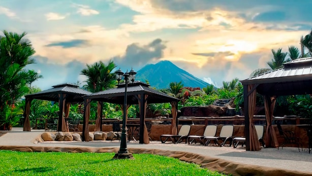 A garden area with outdoor seating, a lamp post, and a view of a mountain. - Volcano Lodge Hotel & Thermal Experience (La Fortuna)