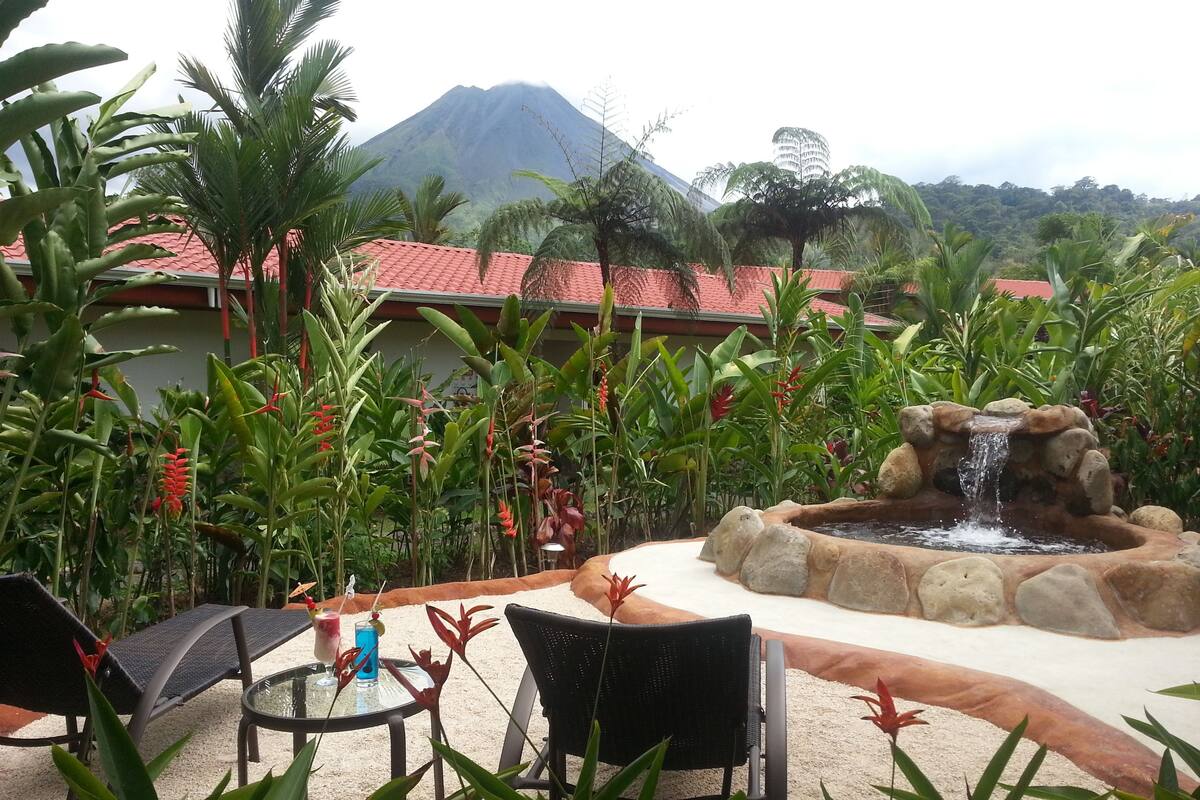 Un espace patio avec des sièges d’extérieur, une petite fontaine et une vue sur les montagnes.