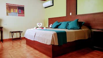 Un lit bien fait, agrémenté de coussins turquoise, d’une tête de lit en bois et d’un climatiseur fixé au mur.