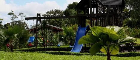 A playground with a blue slide and a wooden playhouse.