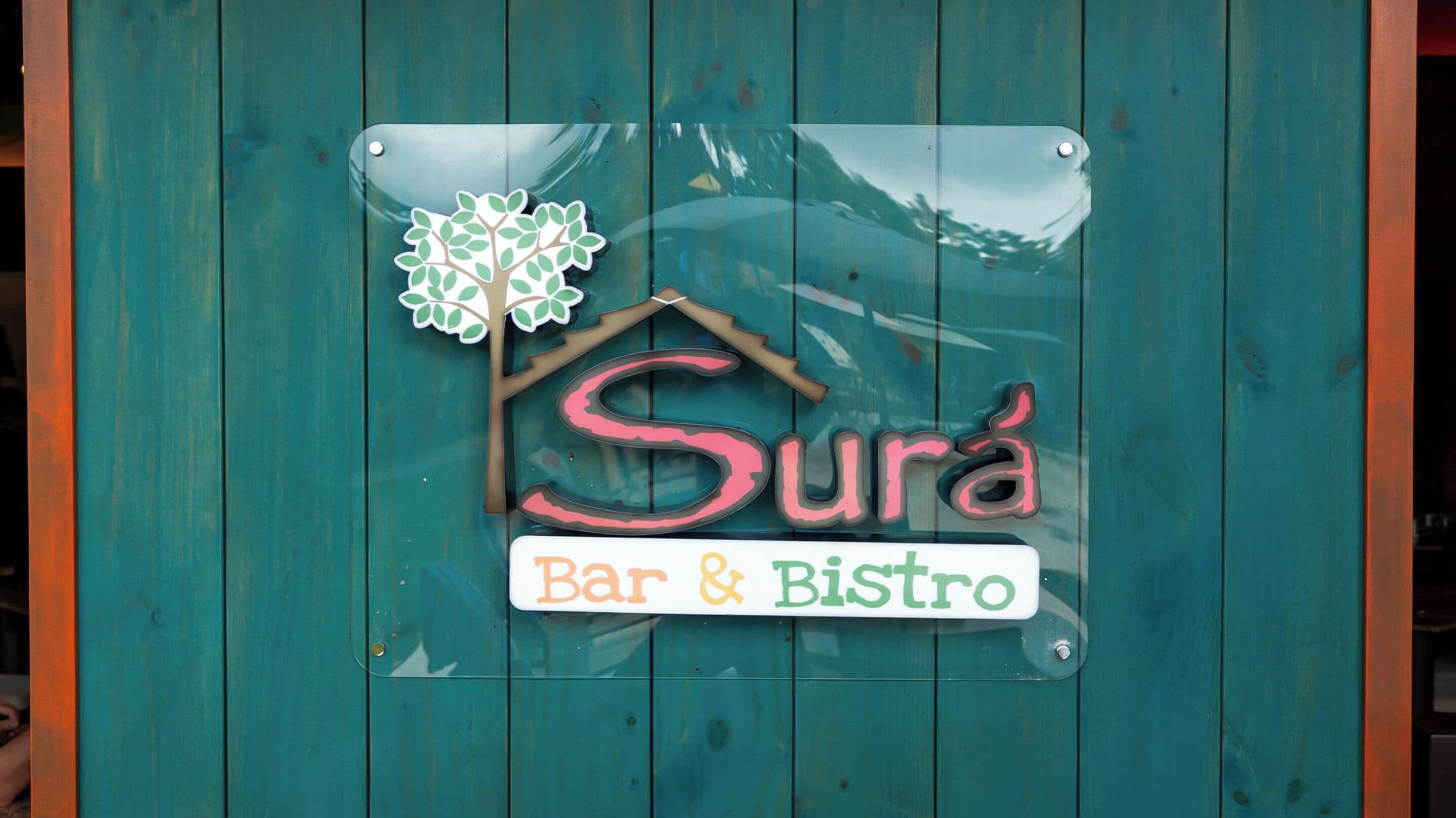 Placa para 'Surá Bar & Bistro' com um desenho de árvore e casa.