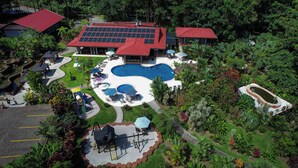 A resort with a large pool, solar panels, and lush landscaping. - Volcano Lodge Hotel & Thermal Experience (La Fortuna)