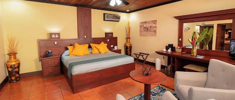 Une chambre d’hôtel avec un plafond en bois, un lit avec des oreillers orange, un bureau avec un ordinateur et une chaise.