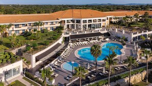 A resort with a large swimming pool, multiple lounge areas, and a view of the surrounding landscape. - Wyndham Grand Algarve Quinta do Lago (Loulé)