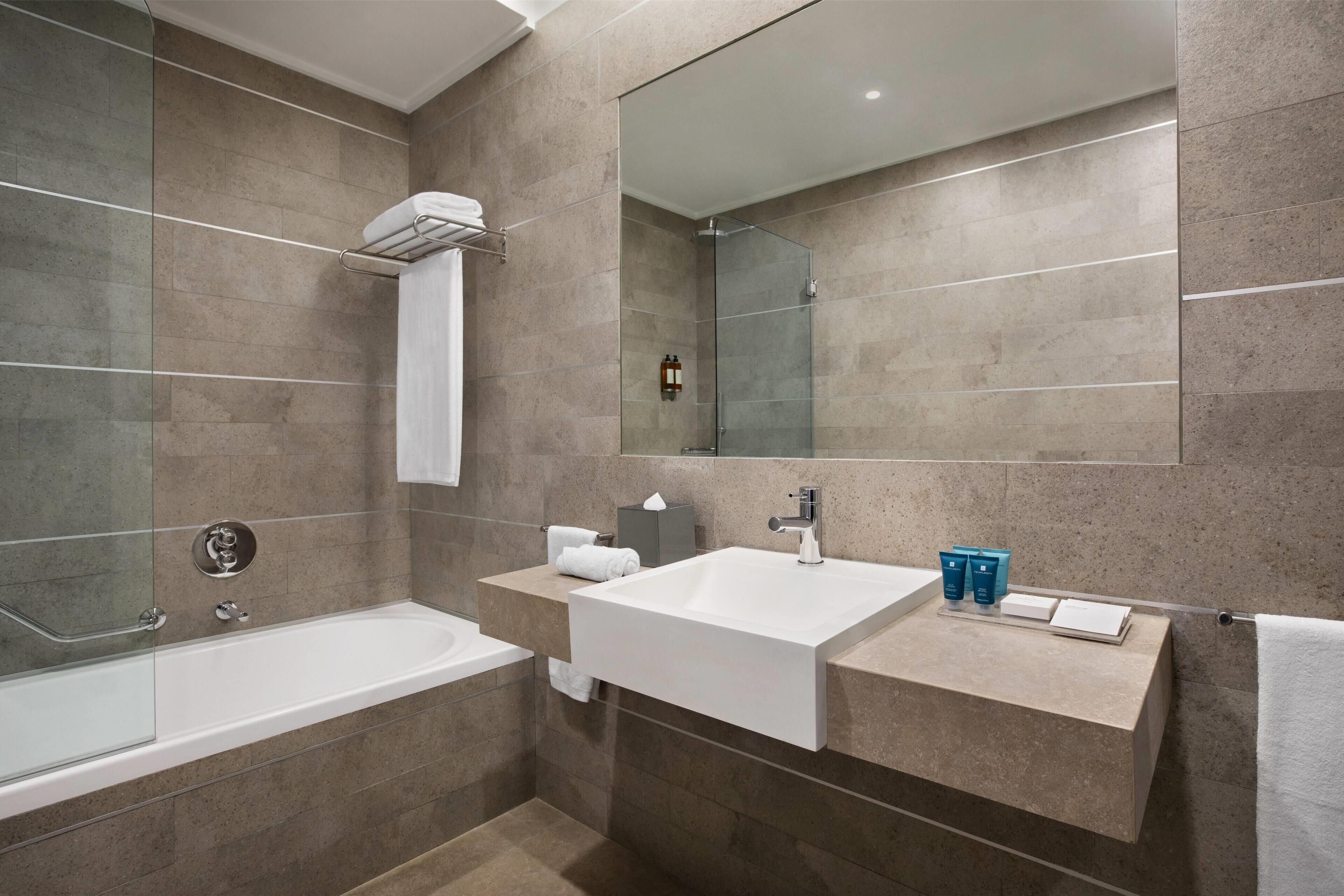 Une salle de bain moderne avec une grande baignoire, un meuble-lavabo avec un miroir et un espace douche.