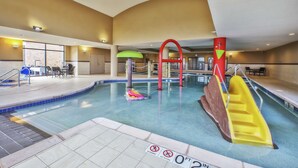 An indoor swimming pool with a slide, a diving board, and a no diving sign.