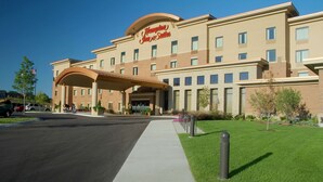 A Hampton Inn & Suites hotel with a covered entrance, a parking lot, and well-maintained landscaping.