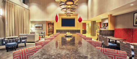 A spacious conference room with a long table, multiple chairs, and a modern chandelier.