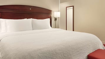 A neatly made bed with white linens, a wooden headboard, and red upholstered benches at the foot of the bed.