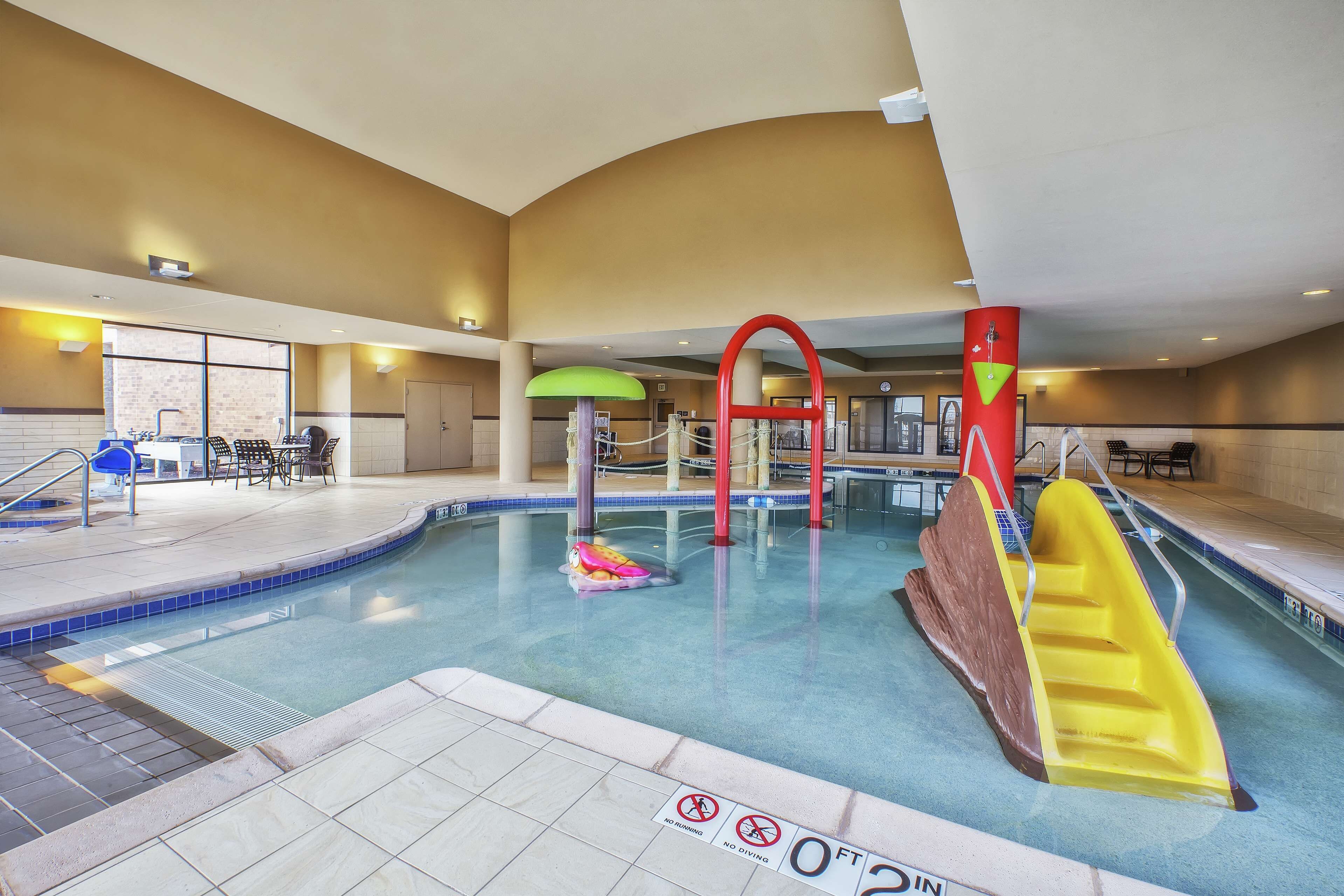 An indoor swimming pool with a slide, a diving board, and a no diving sign.