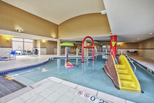 An indoor swimming pool with a slide, a diving board, and a no diving sign.