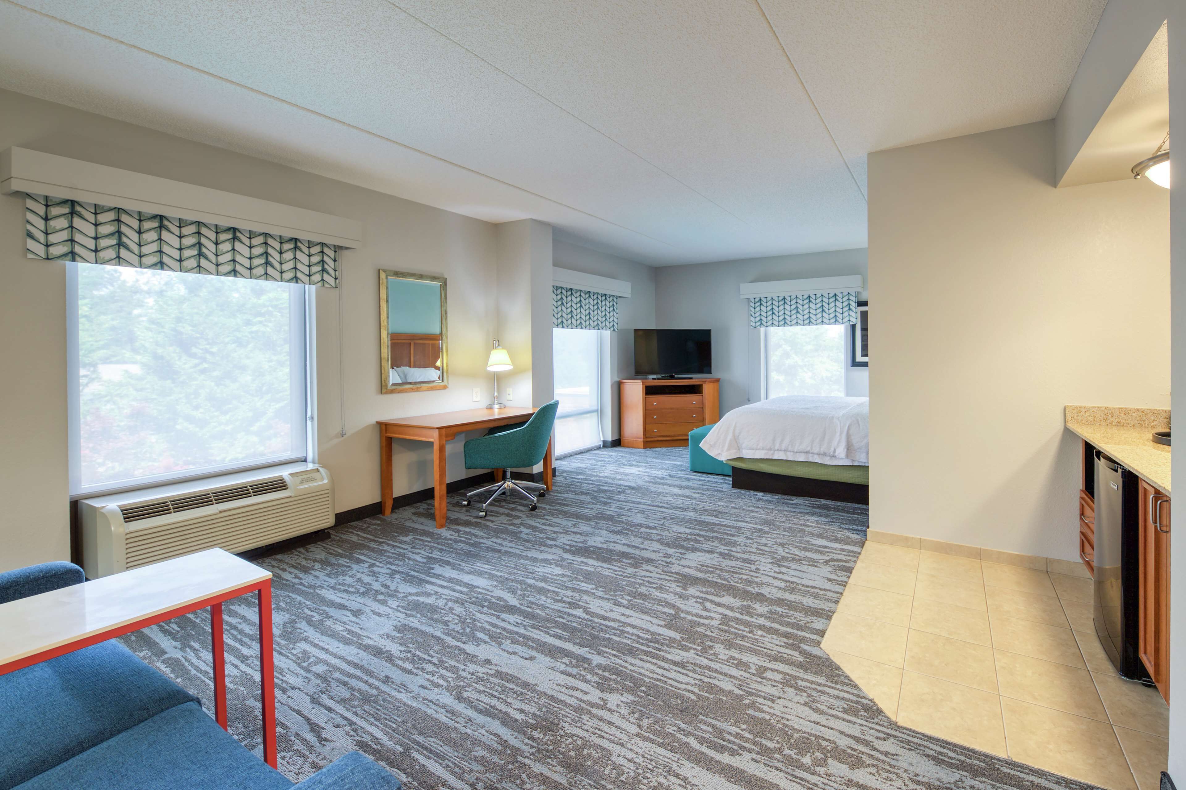 Une chambre d’hôtel équipée d’un bureau, d’une chaise, d’un lit, d’une télévision et d’une kitchenette.