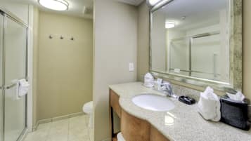 A bathroom with a sink, mirror, towel rack, and shower area.