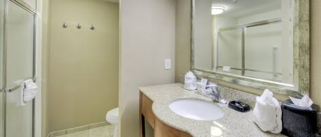 A bathroom with a sink, mirror, towel rack, and shower area.