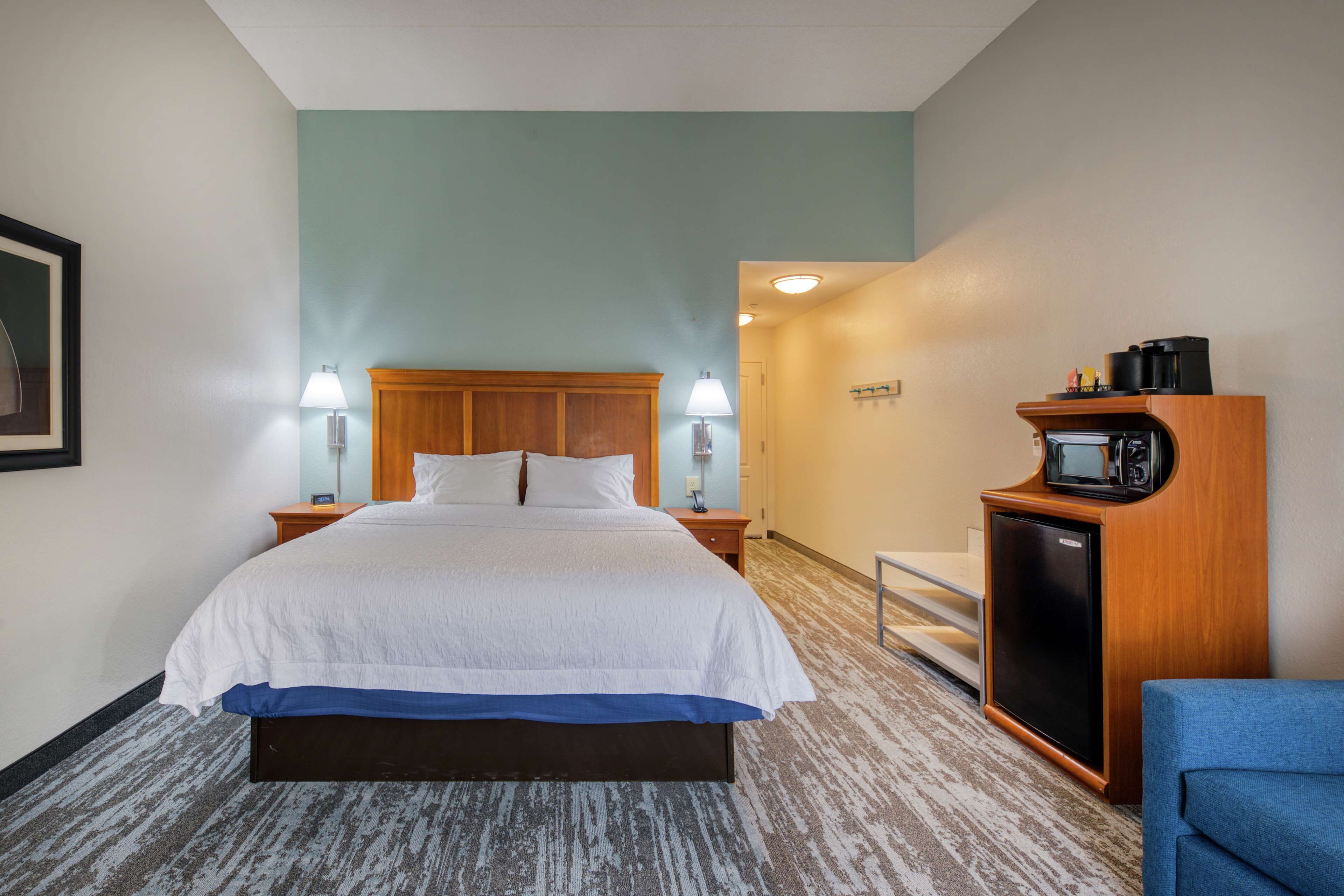 Une chambre d’hôtel avec un grand lit, deux tables de chevet avec des lampes, un four à micro-ondes et un petit coin salon.