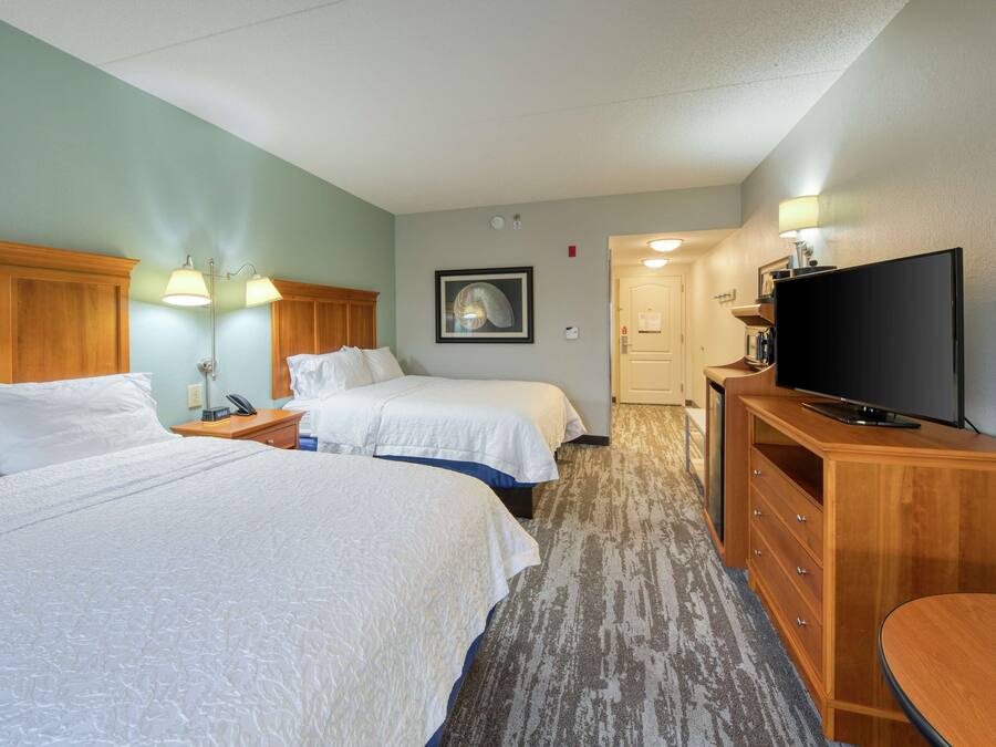 Une chambre d’hôtel avec deux lits, une télévision, une commode et une lampe.