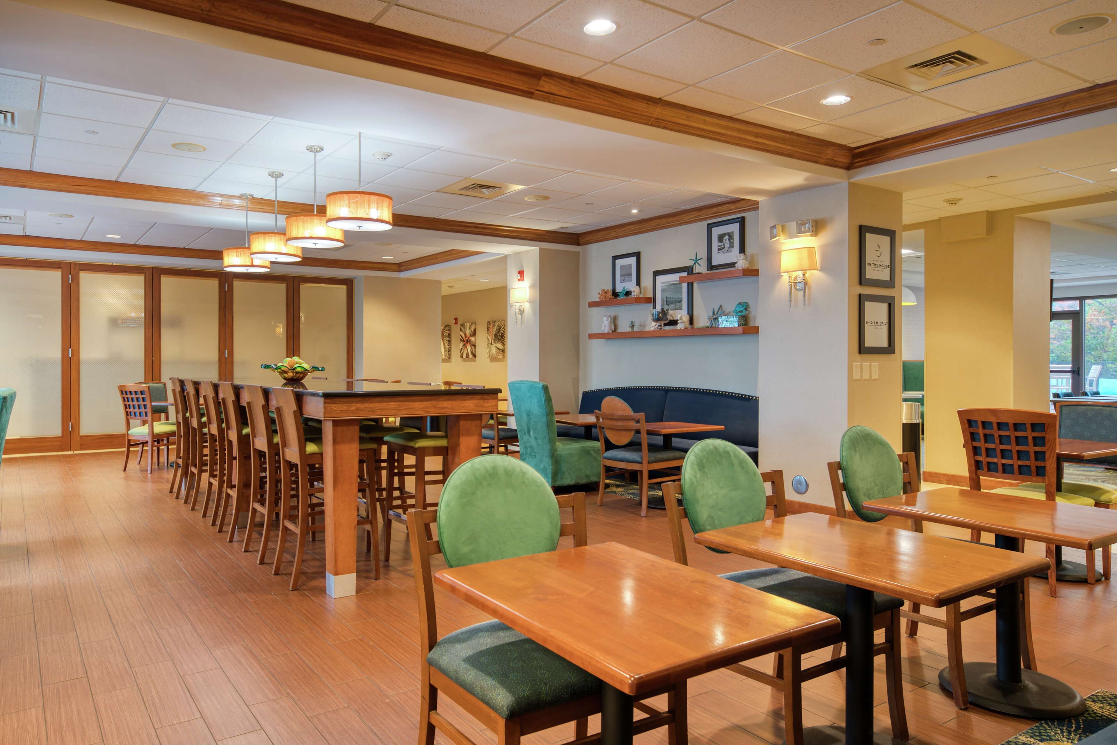A spacious dining area with wooden tables and chairs, a long counter, and a blue sofa.