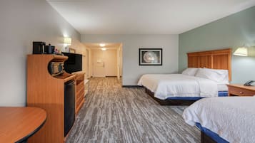 A hotel room with two beds, a desk, a TV, and a bathroom.