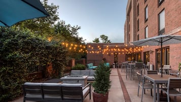Un patio al aire libre con asientos, un pozo de fuego y luces colgantes.