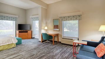 Une chambre d’hôtel équipée d’un lit, d’un bureau, d’une chaise, d’une télévision, d’une lampe et d’un canapé.
