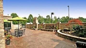An outdoor patio area with stone walls, a brick floor, and outdoor furniture.