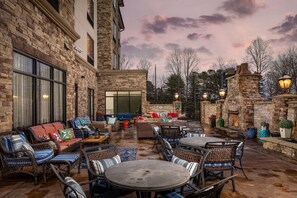 An outdoor patio with stone walls, wicker furniture, and a fire feature.