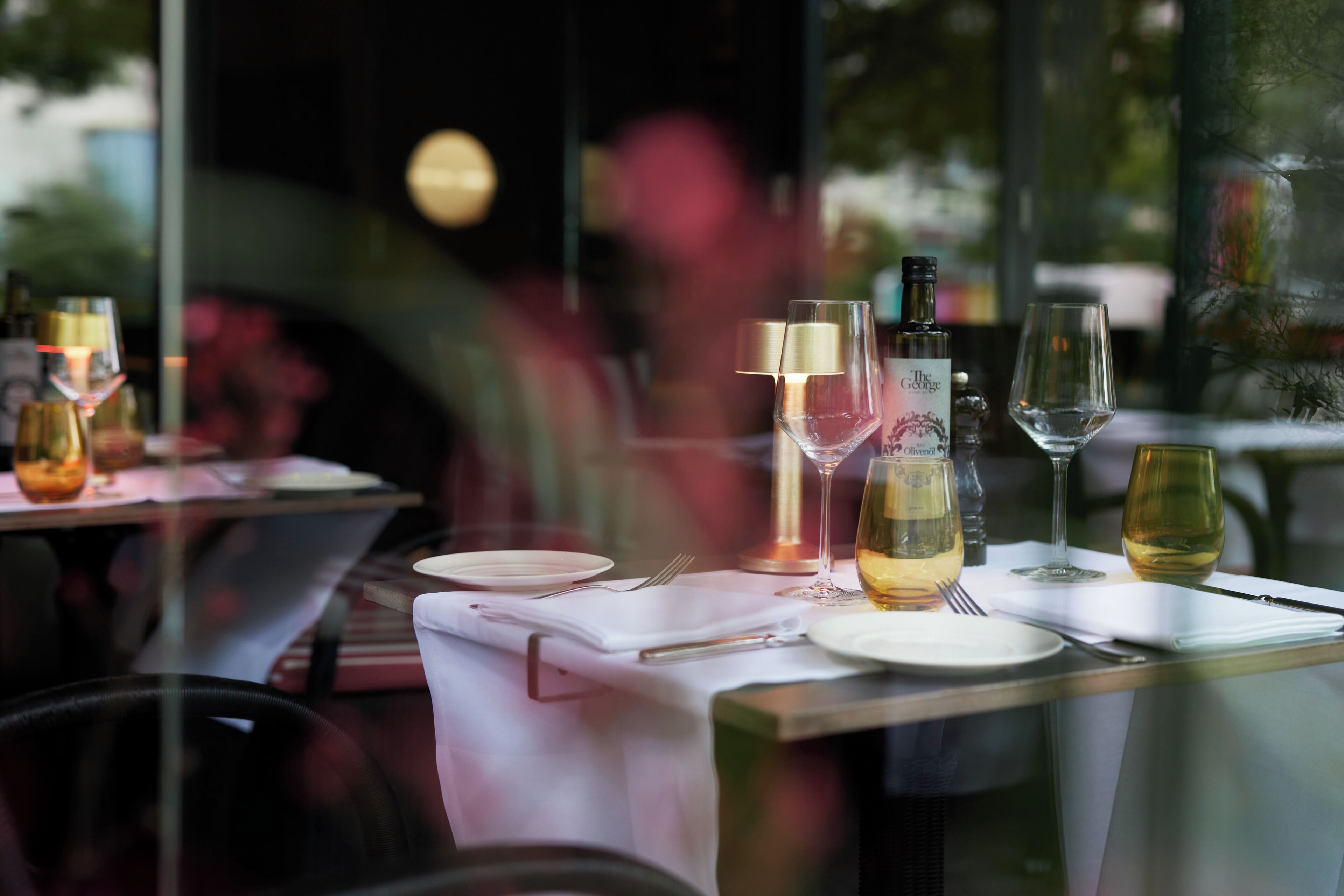 Una mesa dispuesta para una comida, con copas de vino, una botella y cubiertos.