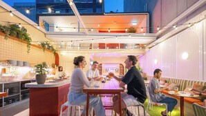 Un área de comedor al aire libre con barra, asientos y vistas a un edificio.