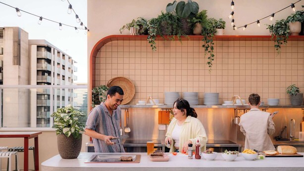 Una cocina moderna con una isla central, plantas en macetas y vistas a la ciudad.