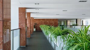 Een moderne hal met marmeren wanden, een donkere vloer en potplanten langs de gang.