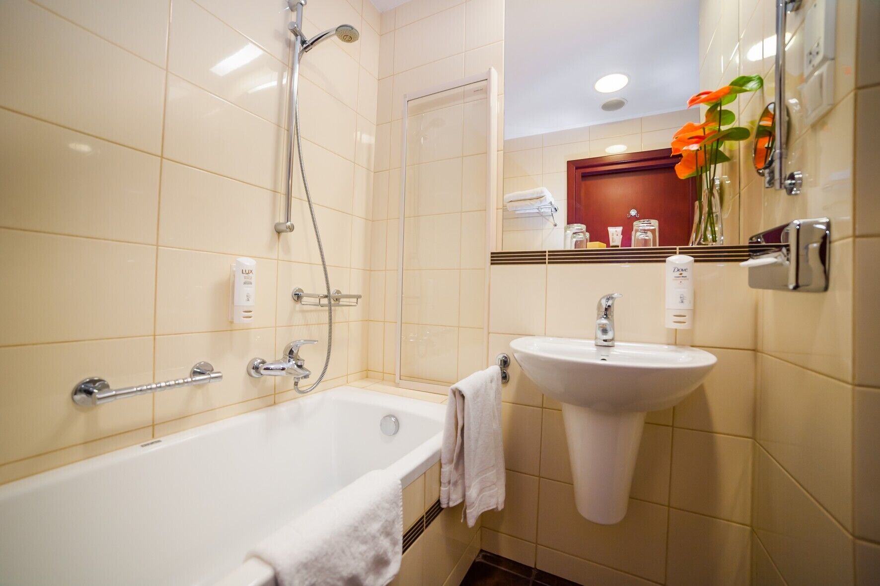 Un baño con bañera, lavamanos, ducha, toallero y espejo.
