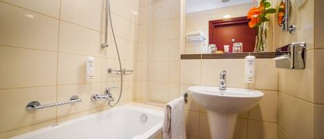 Un baño con bañera, lavamanos, ducha, toallero y espejo.