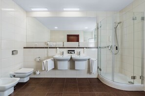 A modern bathroom with a toilet, bidet, two sinks, a shower, and a mirror. - Premier Krakow Hotel (Kraków)