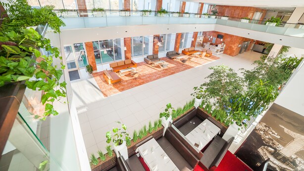 Een meerlaags atrium met zitplekken, glazen balustrades en binnenshuis planten.