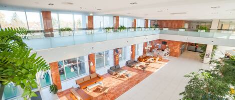A spacious, modern atrium with a high ceiling, multiple seating areas, and abundant natural light.