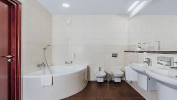 Un baño moderno con bañera, dos inodoros y dos lavamanos.