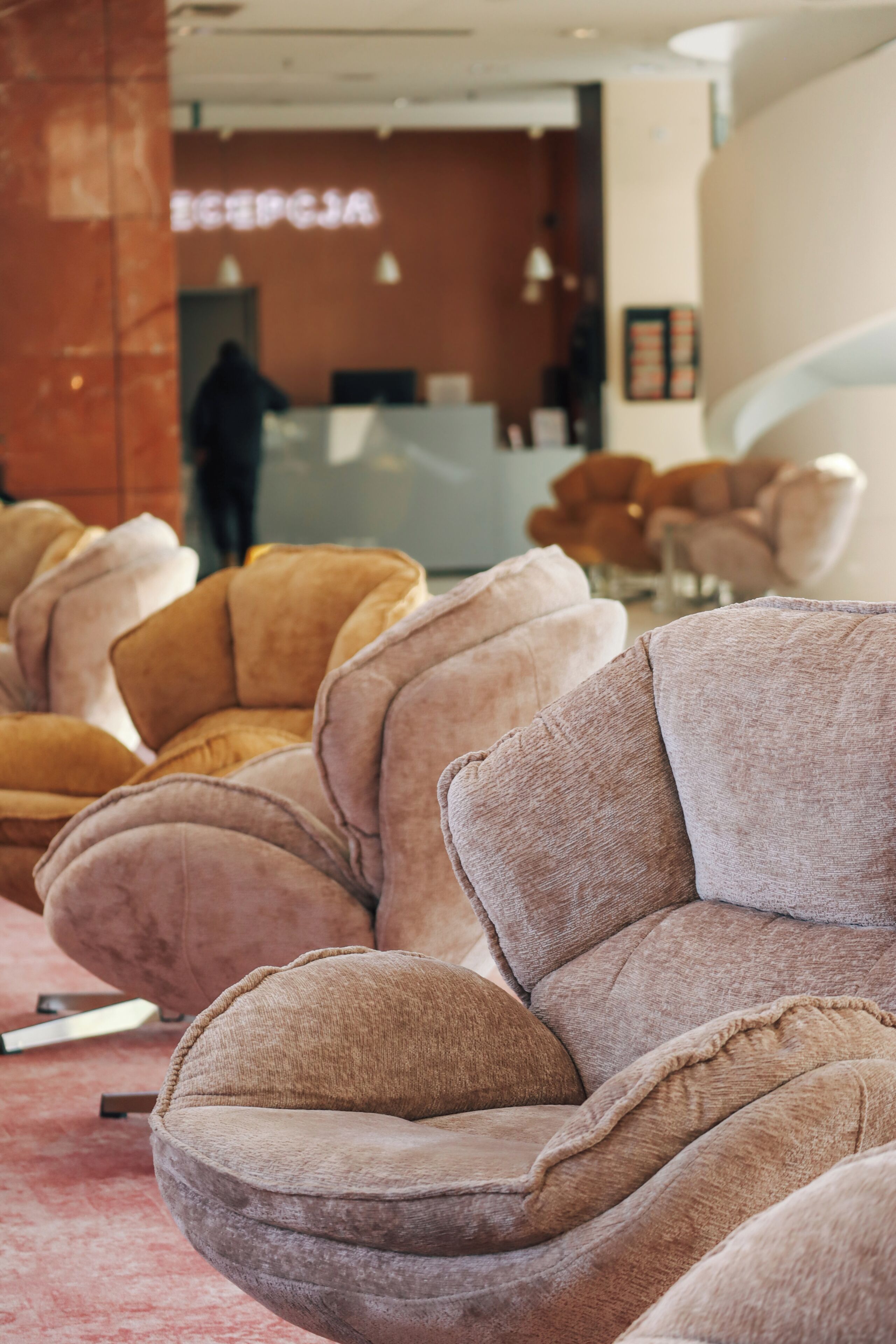 A row of plush, curved armchairs in a modern lobby with a reception desk in the background.