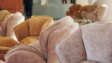 A row of plush, curved armchairs in a modern lobby with a reception desk in the background.