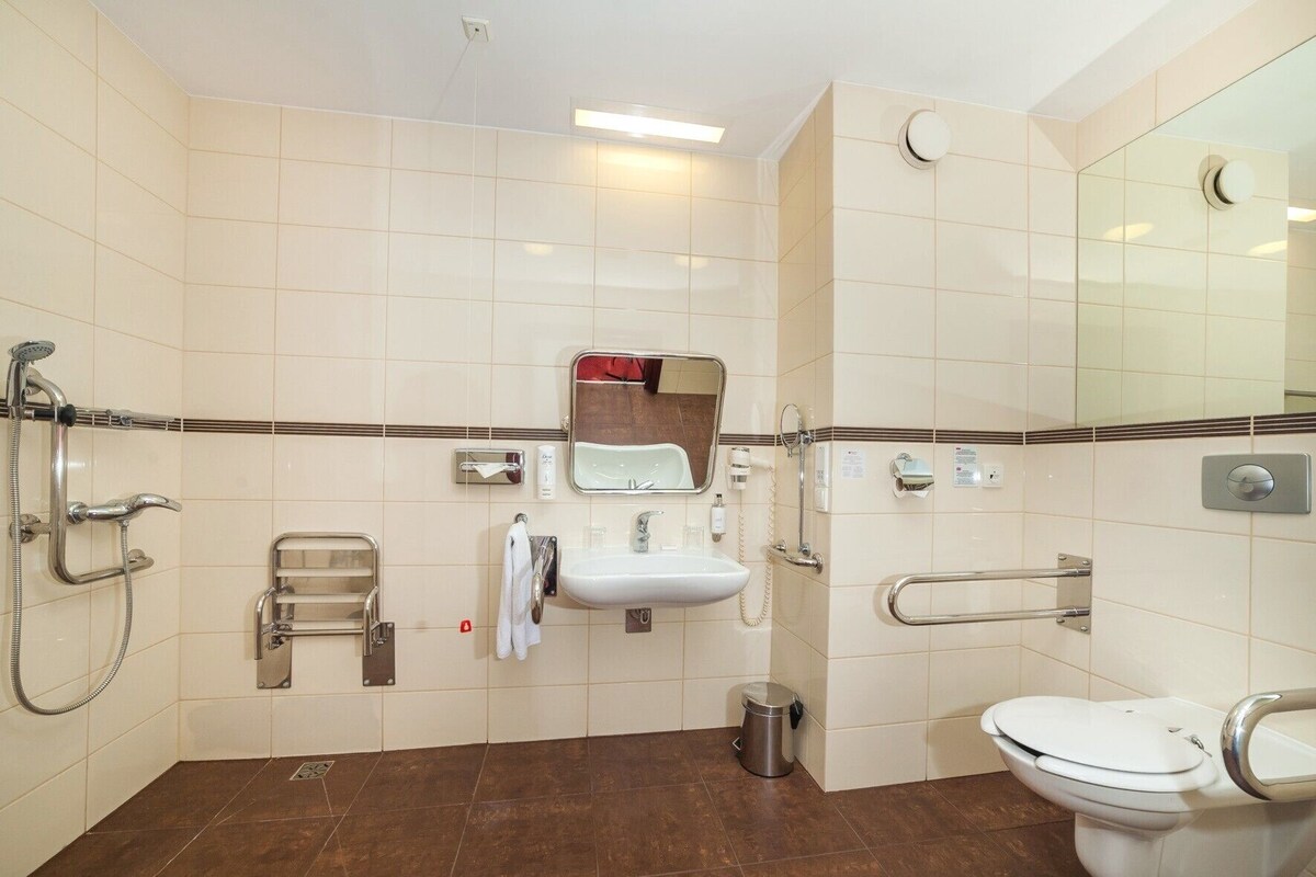 A modern bathroom with a shower, sink, toilet, and a mirror.