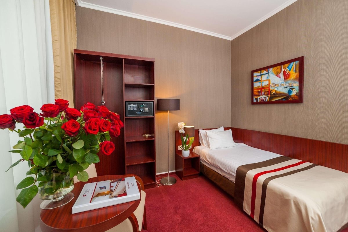 Une chambre d’hôtel avec un lit, une table de chevet, une lampe et un tableau au mur.
