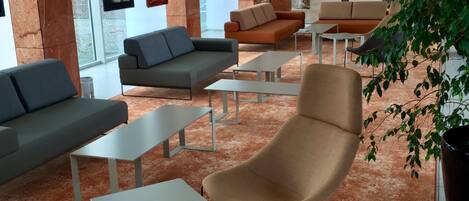 A modern lobby with seating areas, a reception desk, and artwork on the walls.