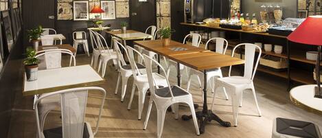 Un espace repas avec des chaises blanches, une table en bois et un buffet proposant divers plats.
