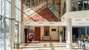 Eine geräumige Lobby mit hoher Decke, einer großen Wandmalerei und einem Empfangsbereich.