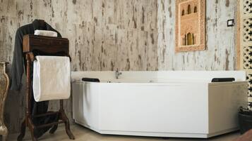 Un baño con una bañera independiente, un perchero y un panel decorativo en la pared.